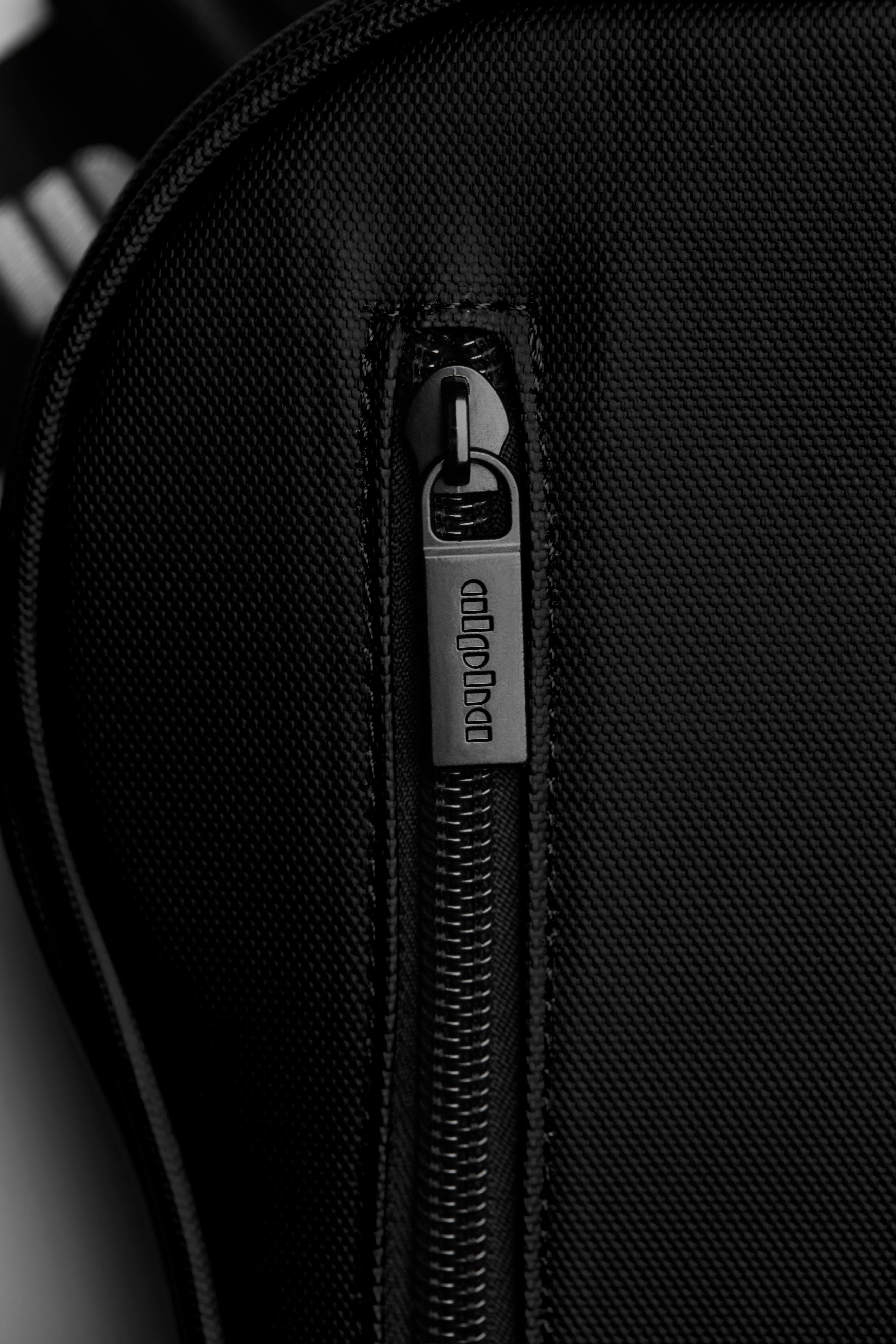 Close-up of a black textured bag with a zipper and visible brand logo.