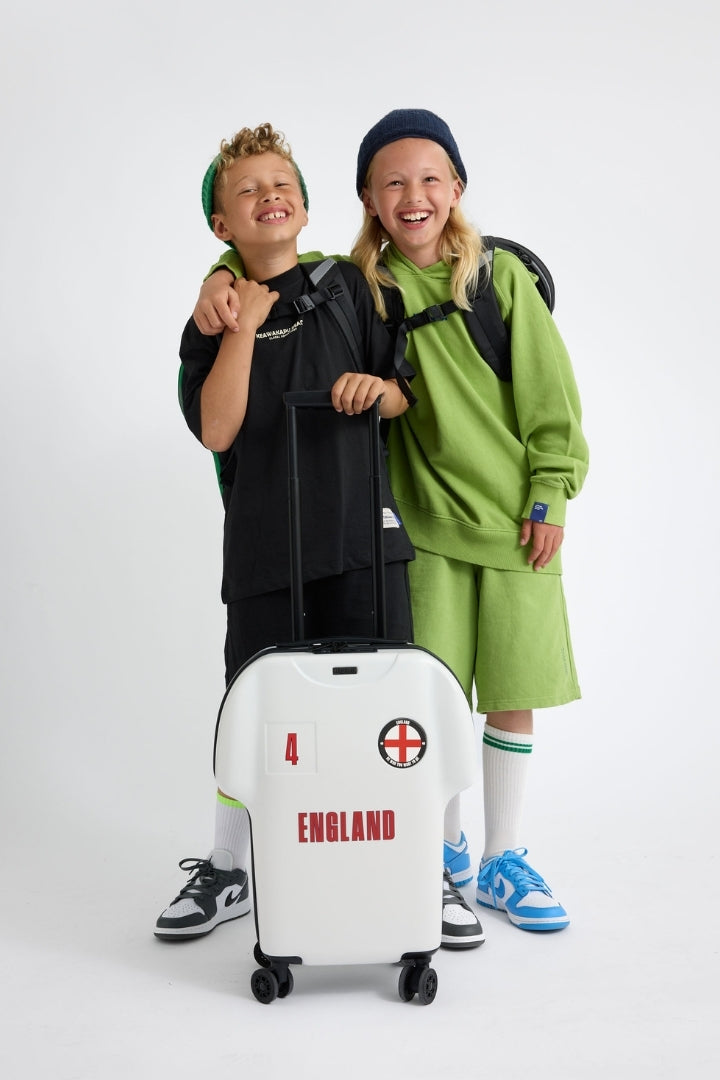 Two children with a white suitcase featuring 'England' text on a white background