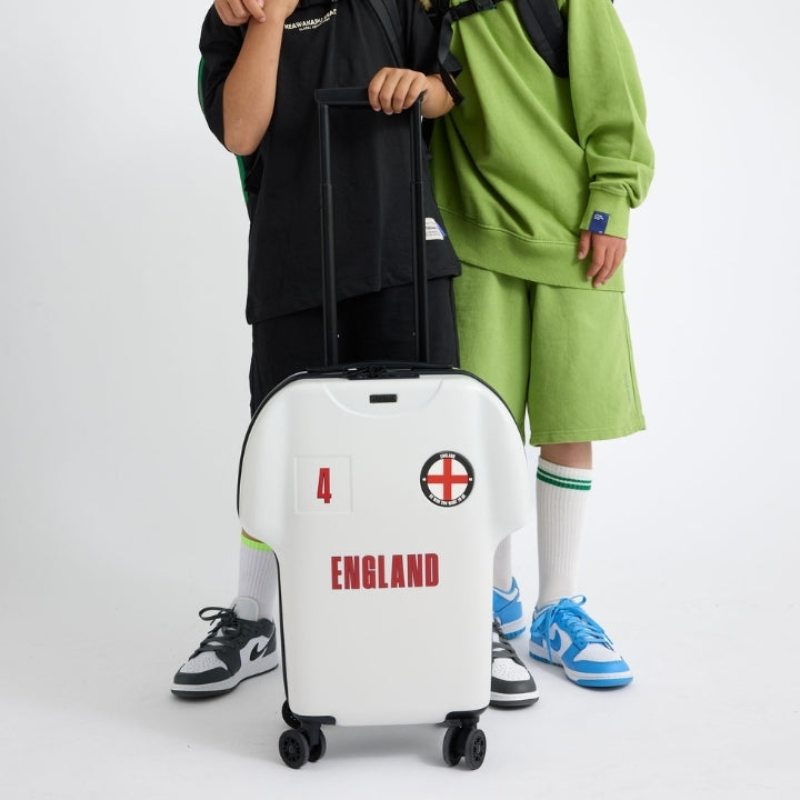 Two children with a white suitcase featuring 'England' text on a white background