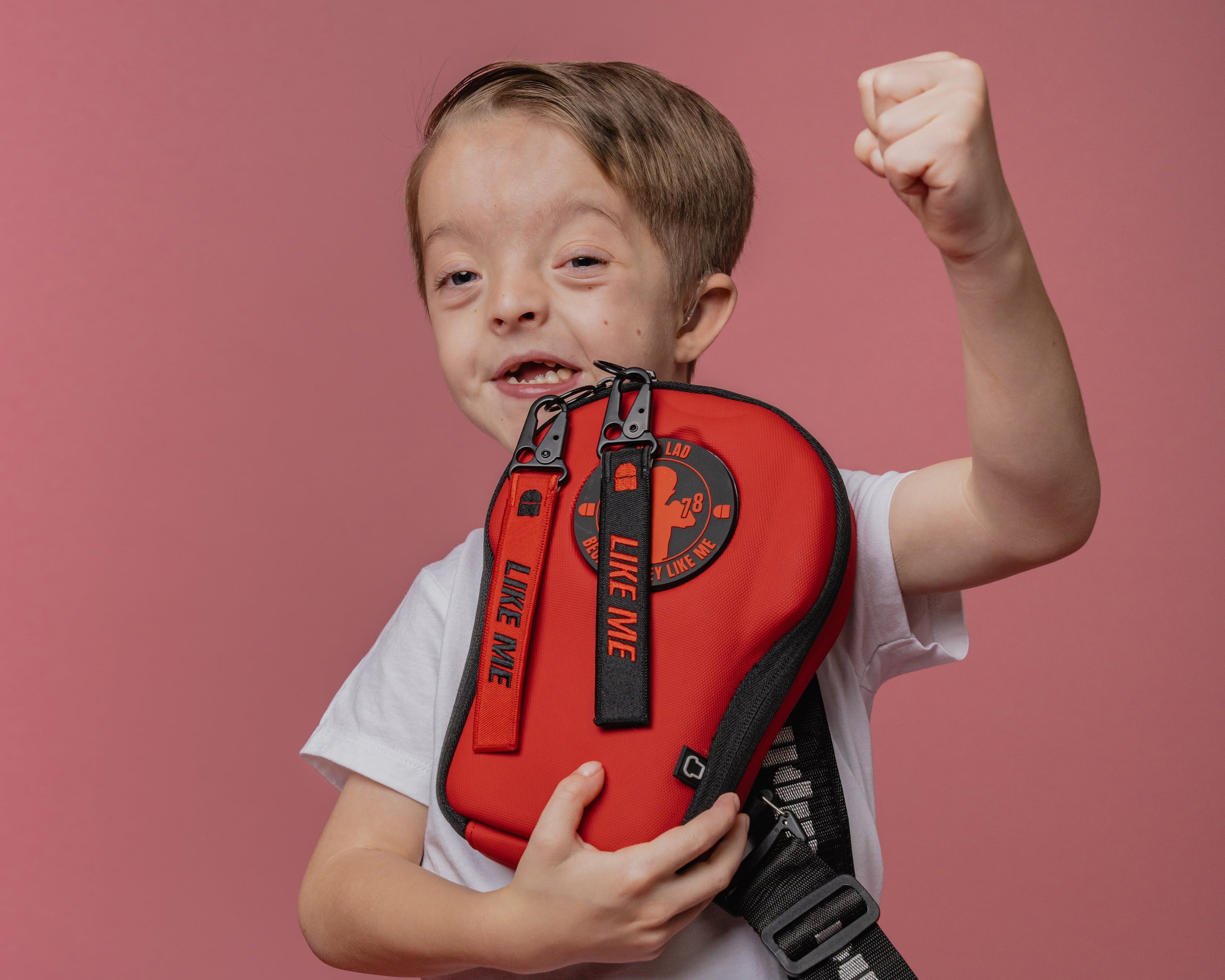 Child holding a red bag with a pink background