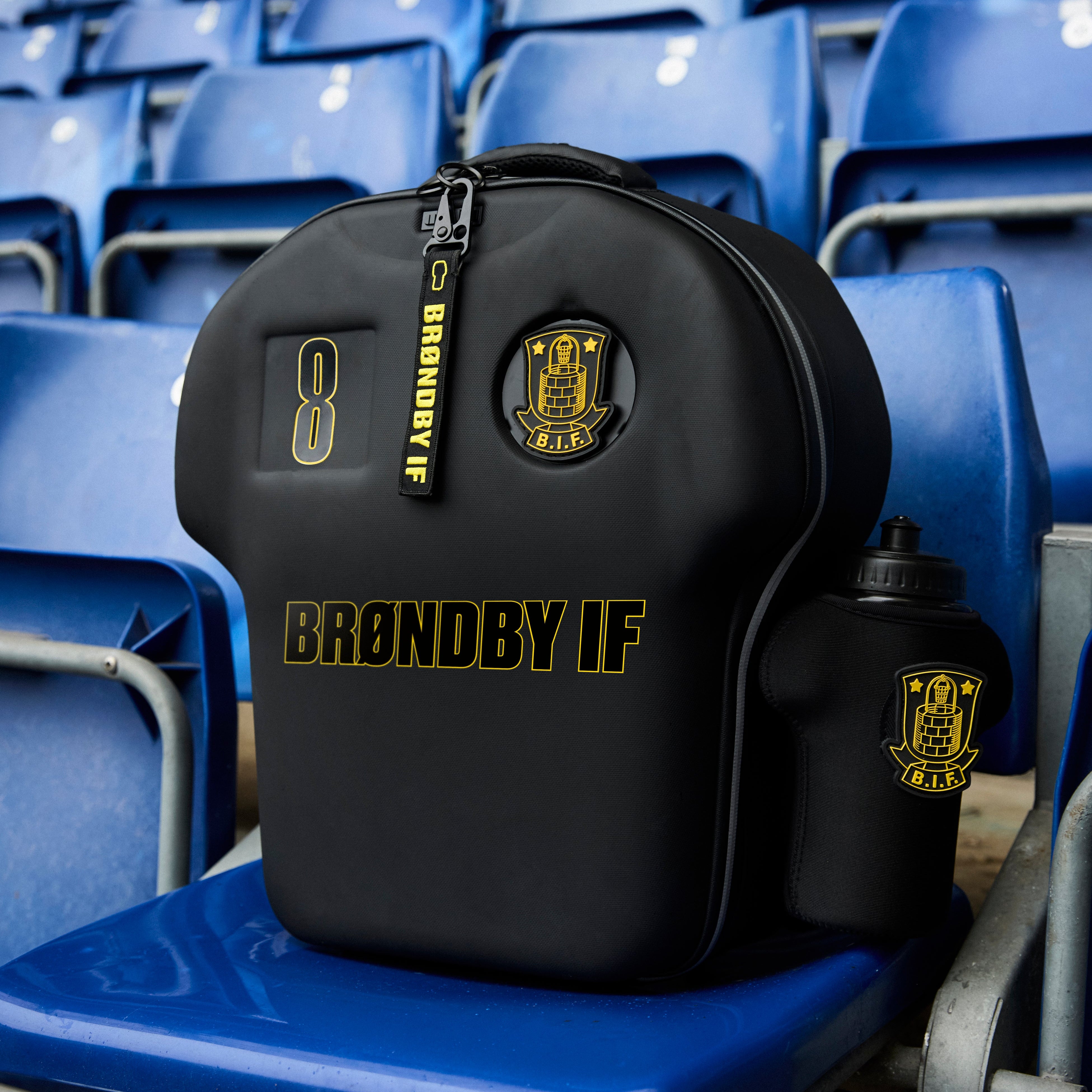 Black sports bag with 'BRØNDBY IF' branding on blue stadium seats.