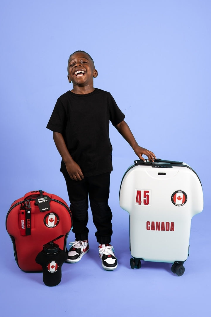 Person standing with a red backpack and white suitcase labeled 'Canada' on a purple background