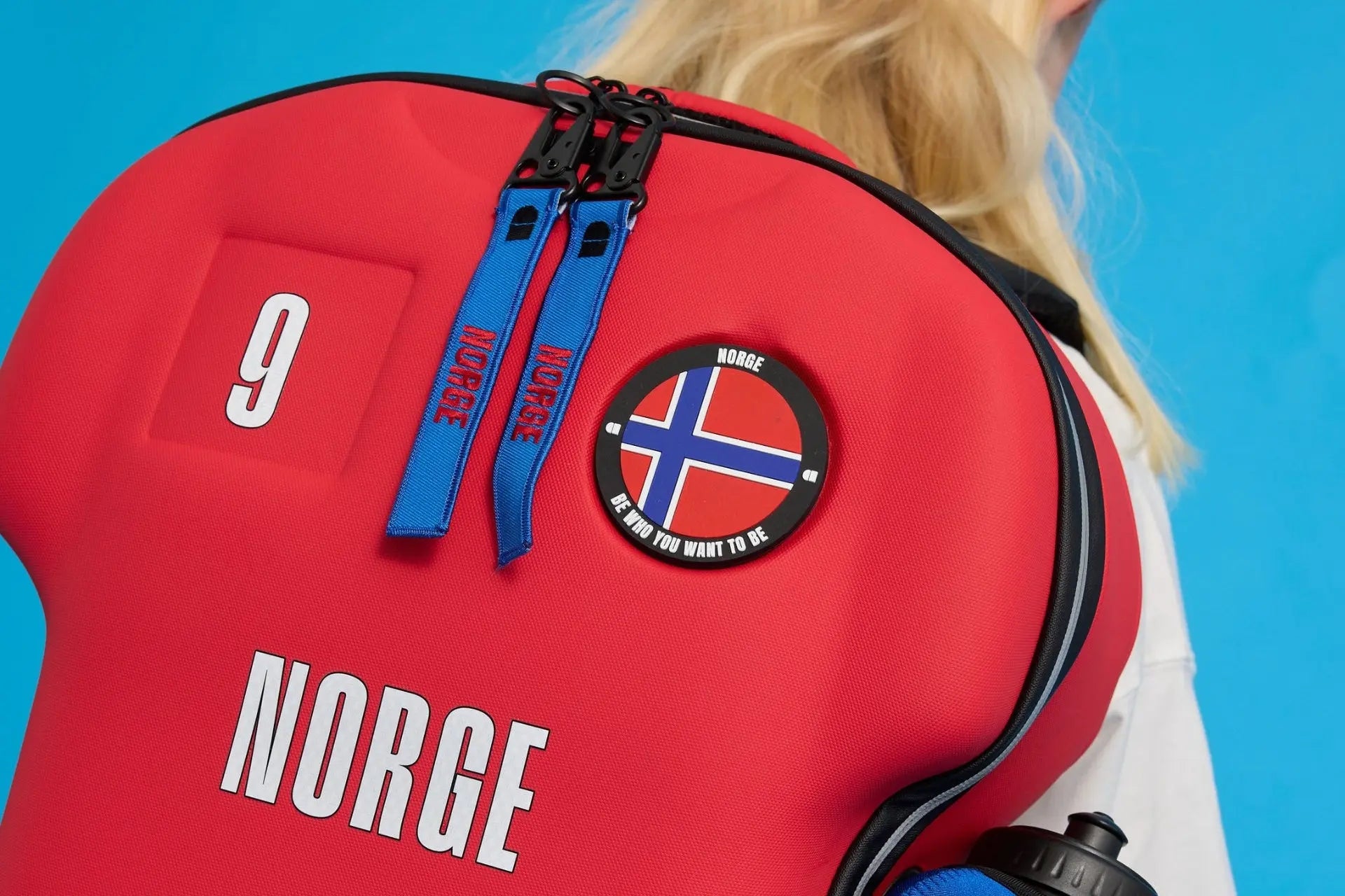 Red backpack with 'Norge' branding and a flag patch on a blue background