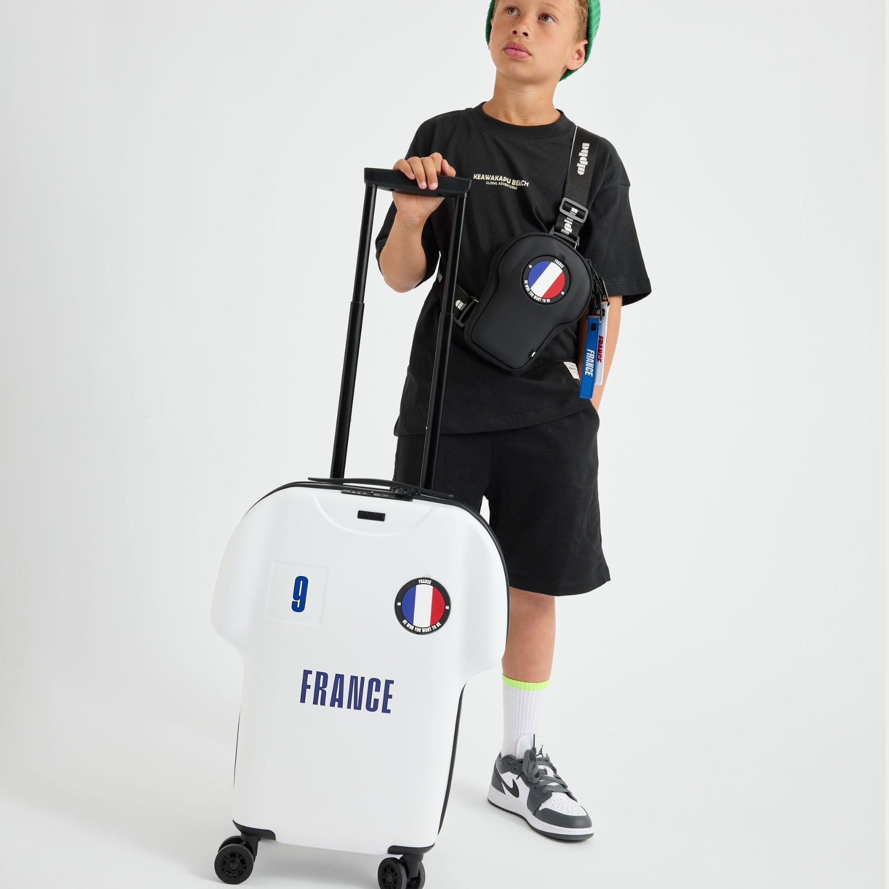 Child holding a white suitcase with 'France' and French flag design on a plain background