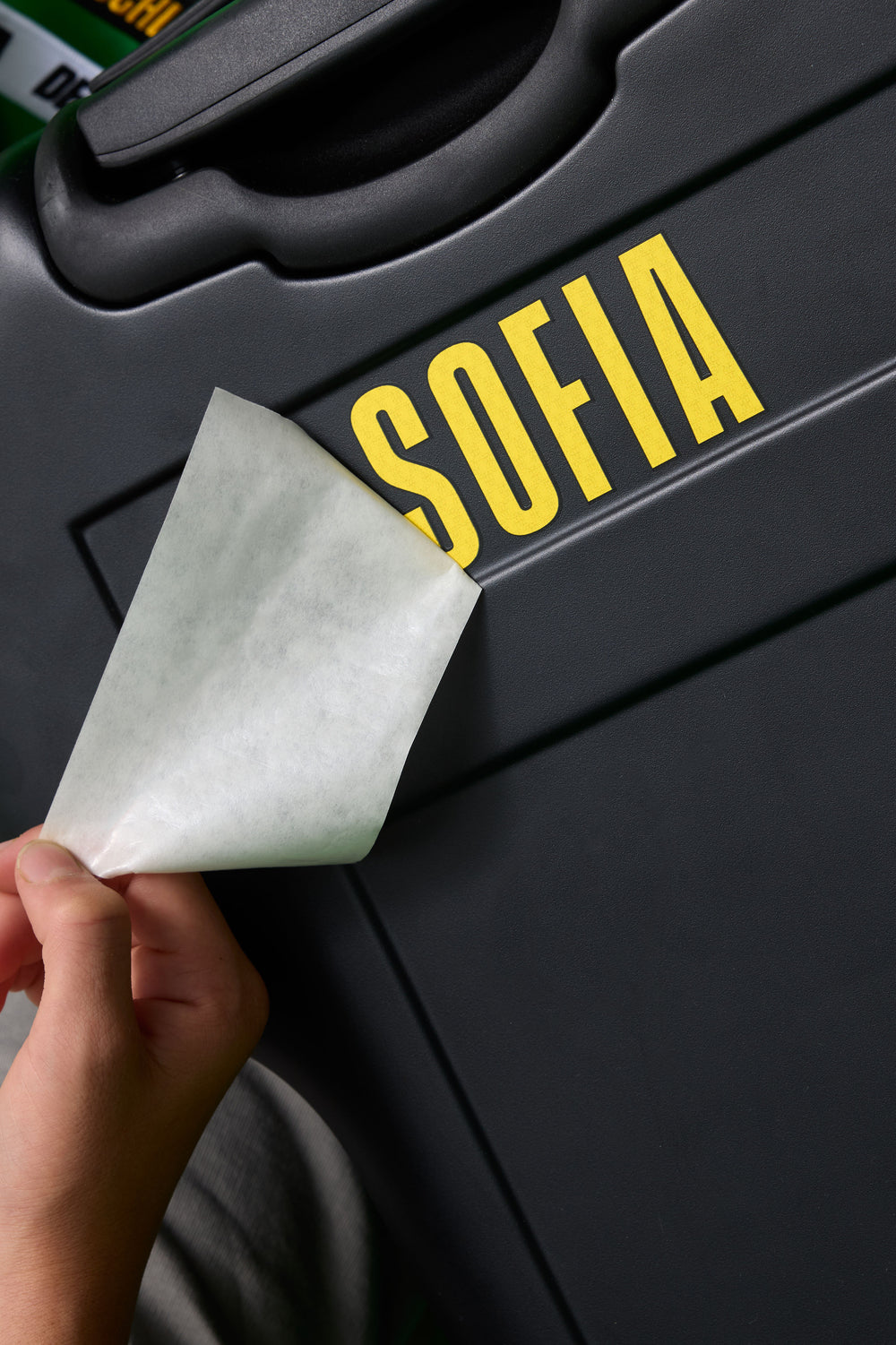 Person applying a yellow 'SOFIA' decal to a black surface
