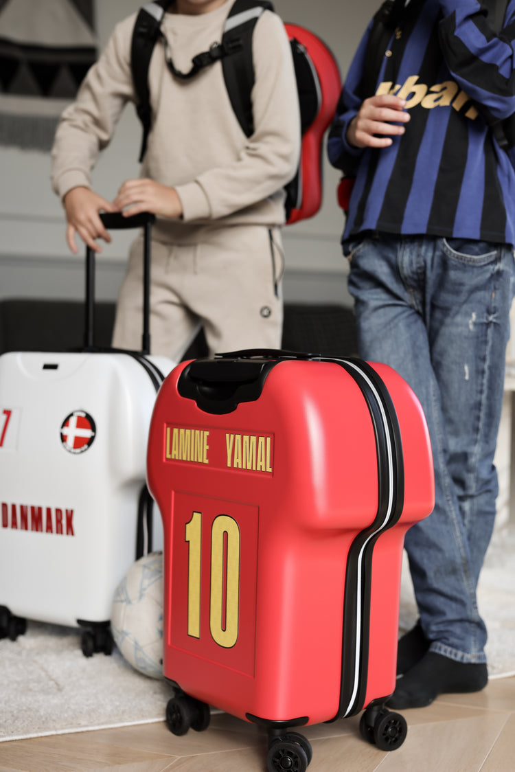Two children with suitcases, one red with 'LAMINE YAMAL' and number '10', the other white with 'DANMARK'.