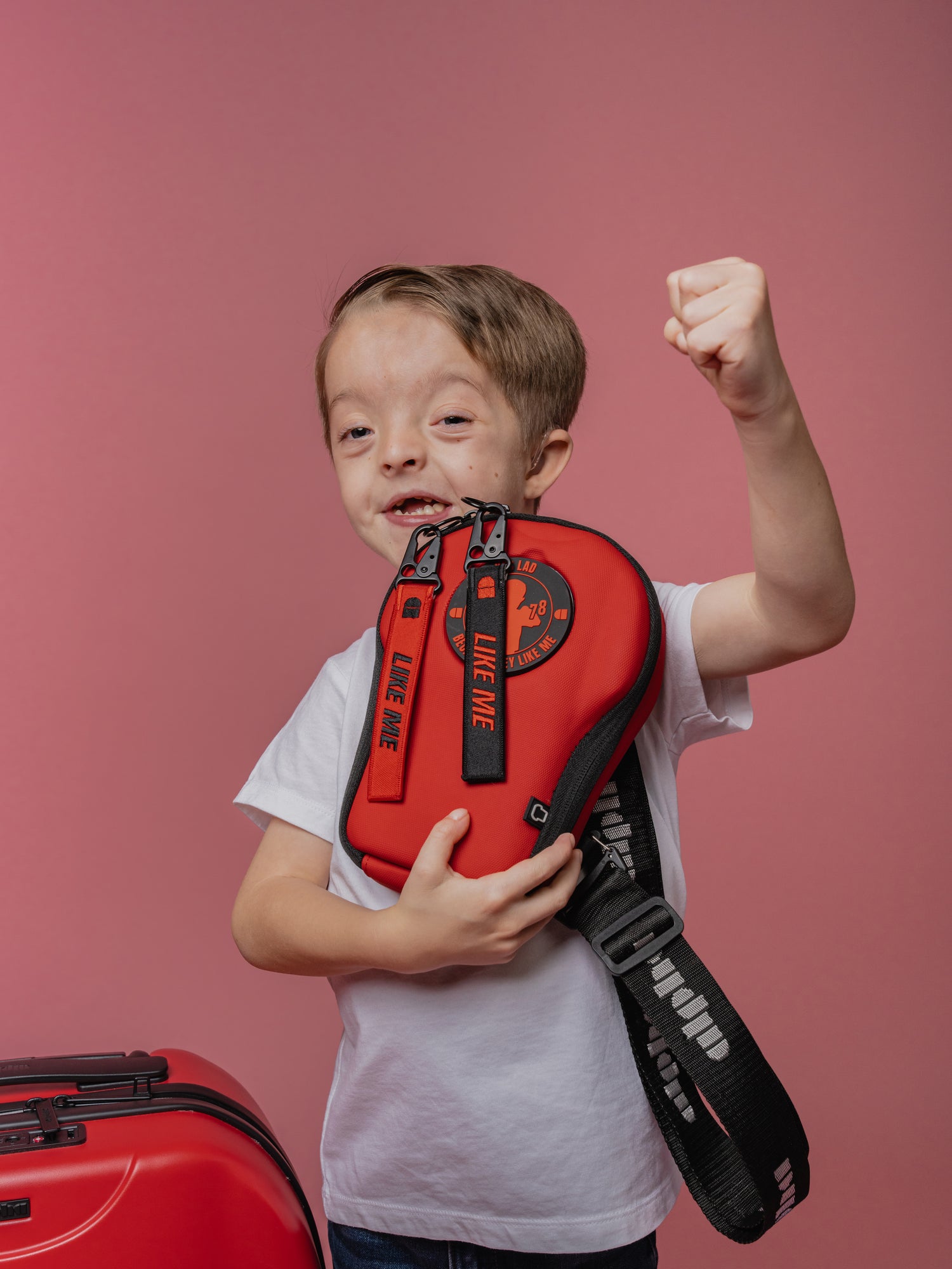 Child holding a red bag with a pink background