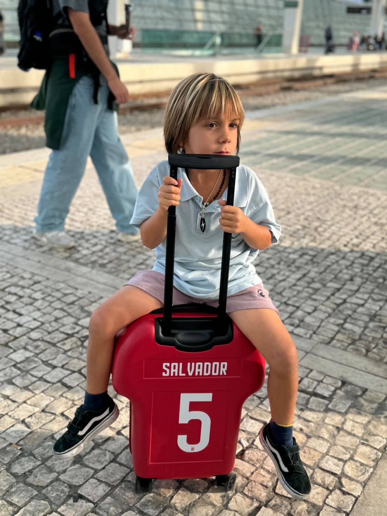 kid sitting on a alpha cabin sl benfica luggage