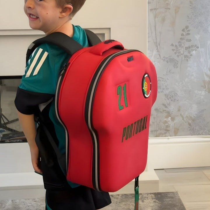 Child wearing a red backpack with 'Portugal' and number '21' design, indoors.
