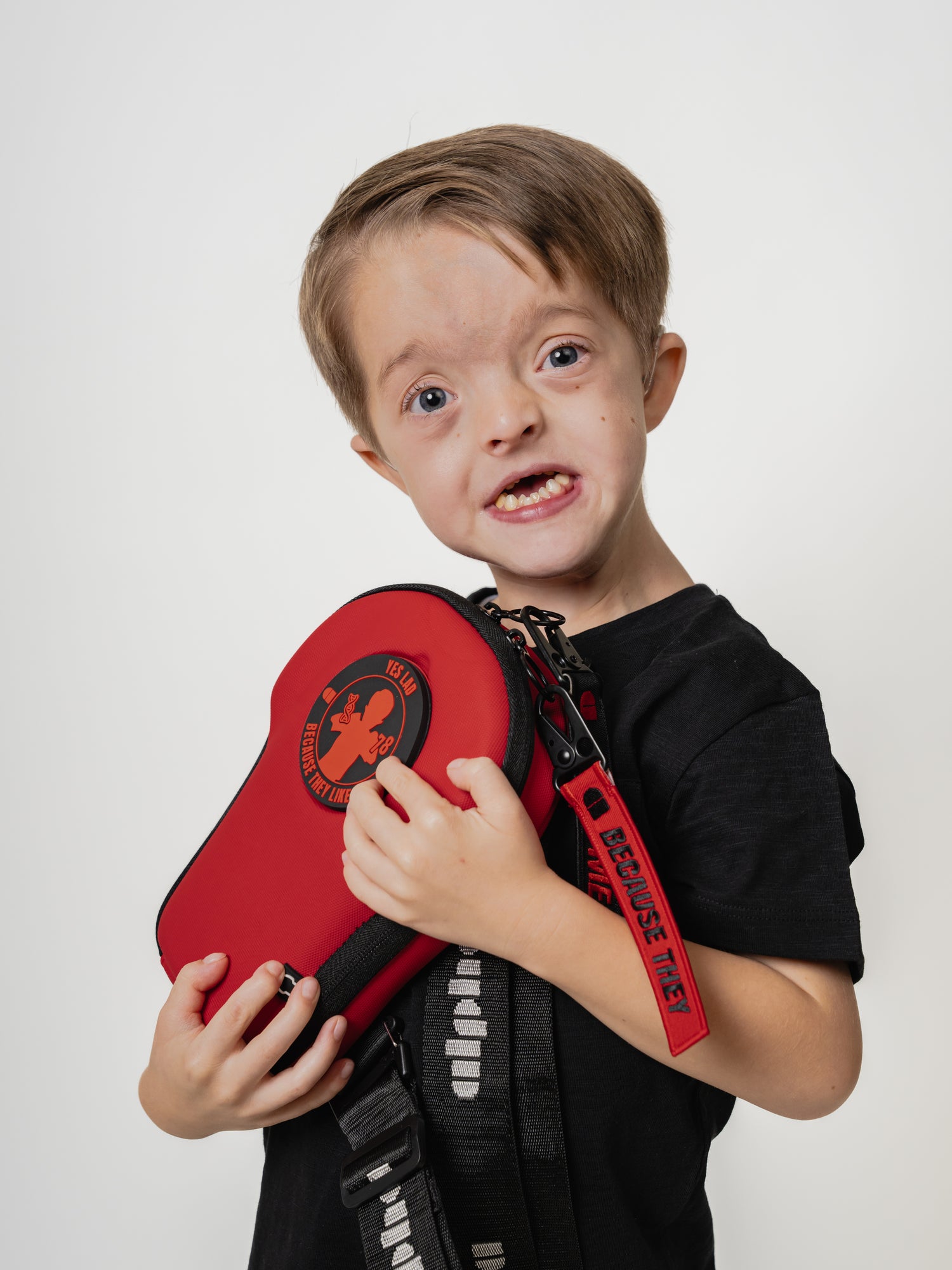 Child holding a red martial arts belt against a white background